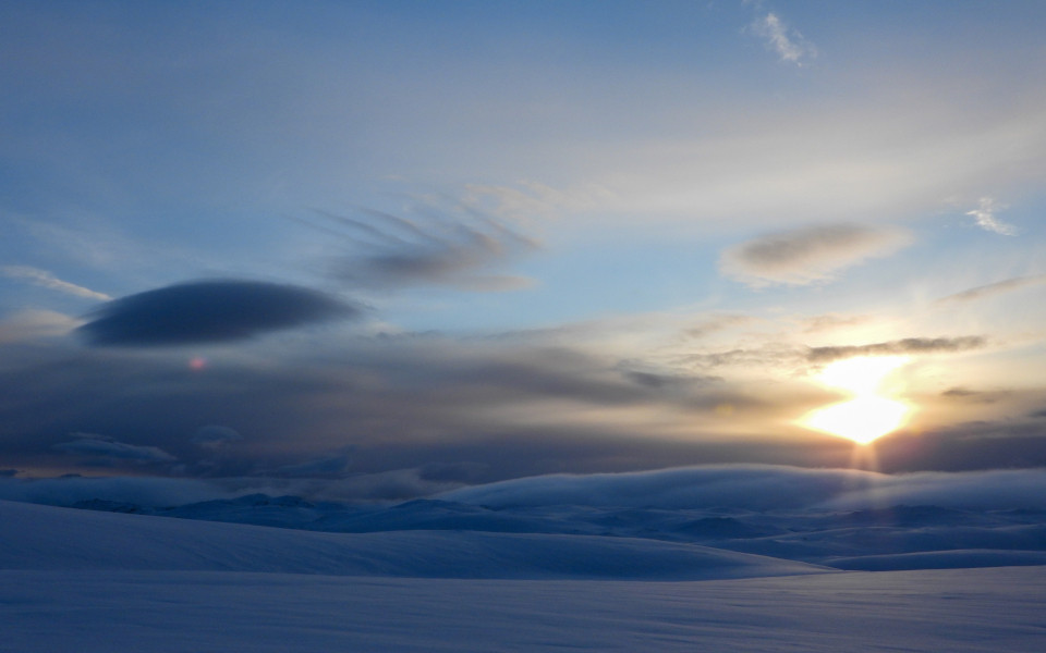Nordkap im Winter mit einer schneebedeckten Landschaft und tief stehender Sonne &uuml;ber dem Horizont.