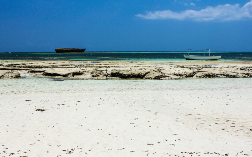 Turtle Bay Beach in Watamu mit weißem Sand, klarem Wasser und einem Boot am Ufer.