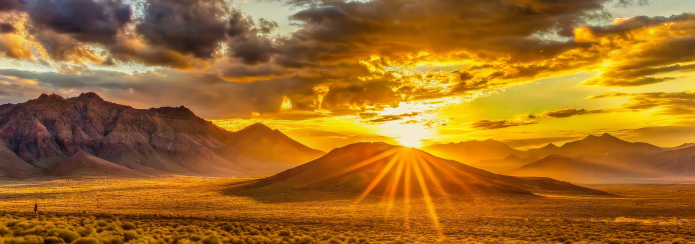 Majestätische Bergsonnenuntergangslandschaft mit goldenen Wolken und Sonnenstrahlen